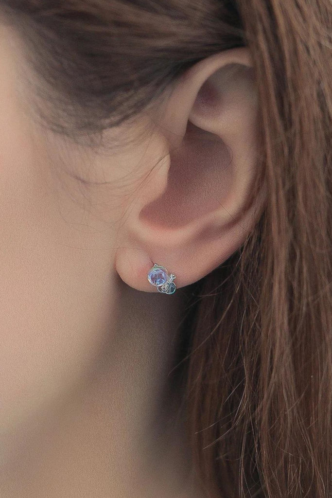 close up of a model wearing a dainty moonstone and sterling silver stud earring