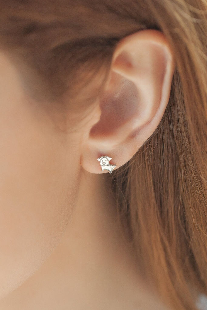 model wearing a solid small cartoon dog stud earring on the earlobe showing the dainty size of the earrings