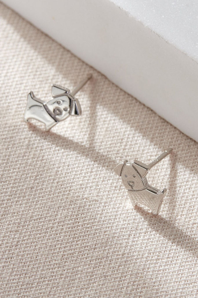 close up of the solid silver dog stud earrings, showing the cartoon like design