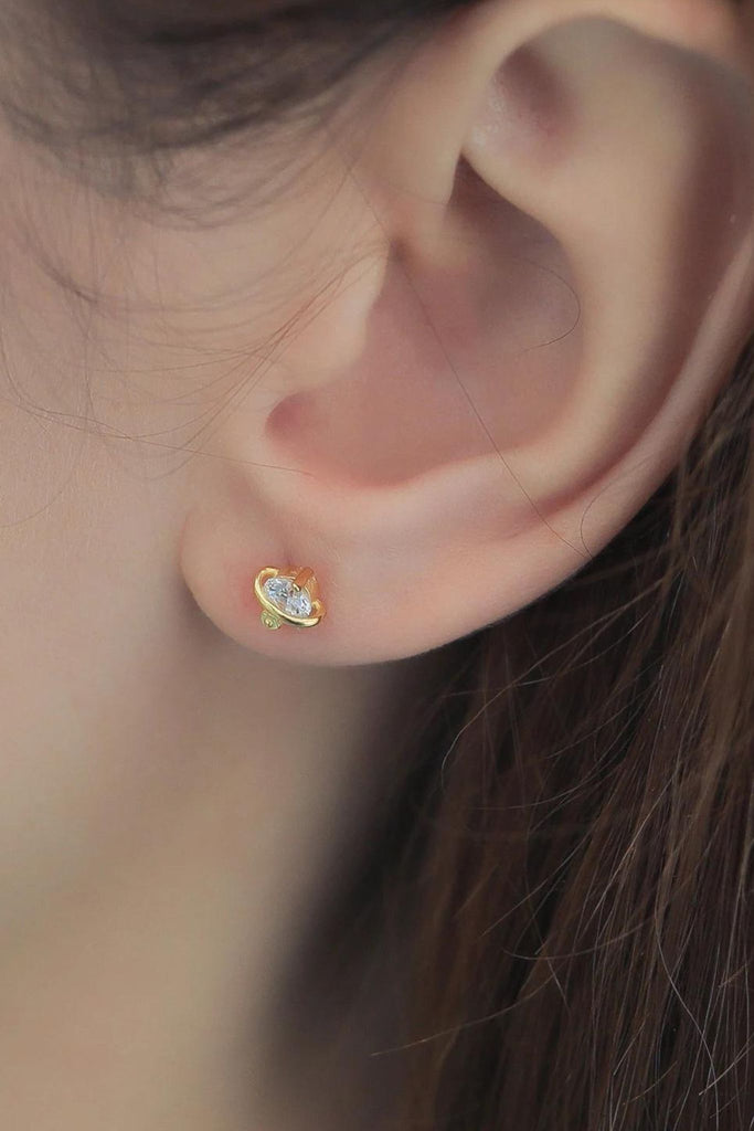 model wearing a small gold sparkly galaxy stud earring on the earlobe, showing the dainty size of the studs