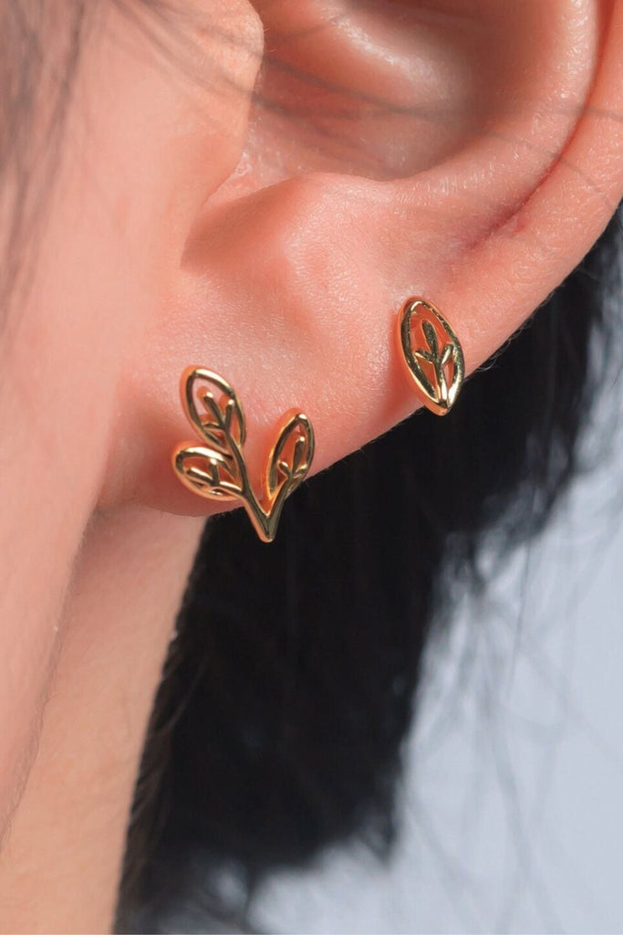 model wearing both of the gold olive leaf studs on the earlobe, showing that they can be worn as stacking earrings as well as one on each ear