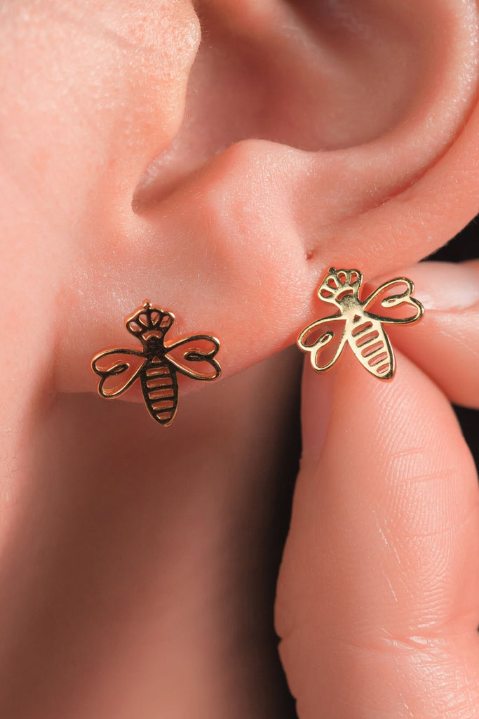 model wearing a gold crown and bee stud earring on the earlobe showing the size of the earrings