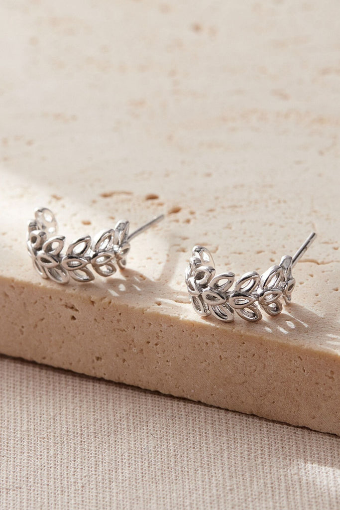 close up of the silver coloured olive leaf half hoop earrings, the olive leaves are in three adjoining rows