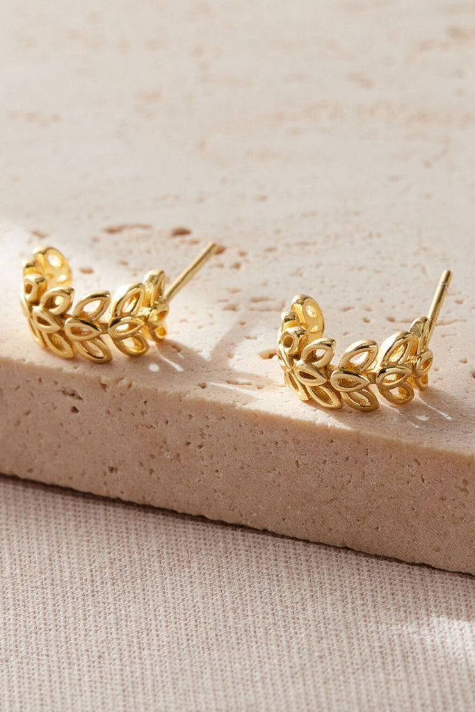 close up of the gold coloured olive leaf half hoop earrings, the olive leaves are in three adjoining rows