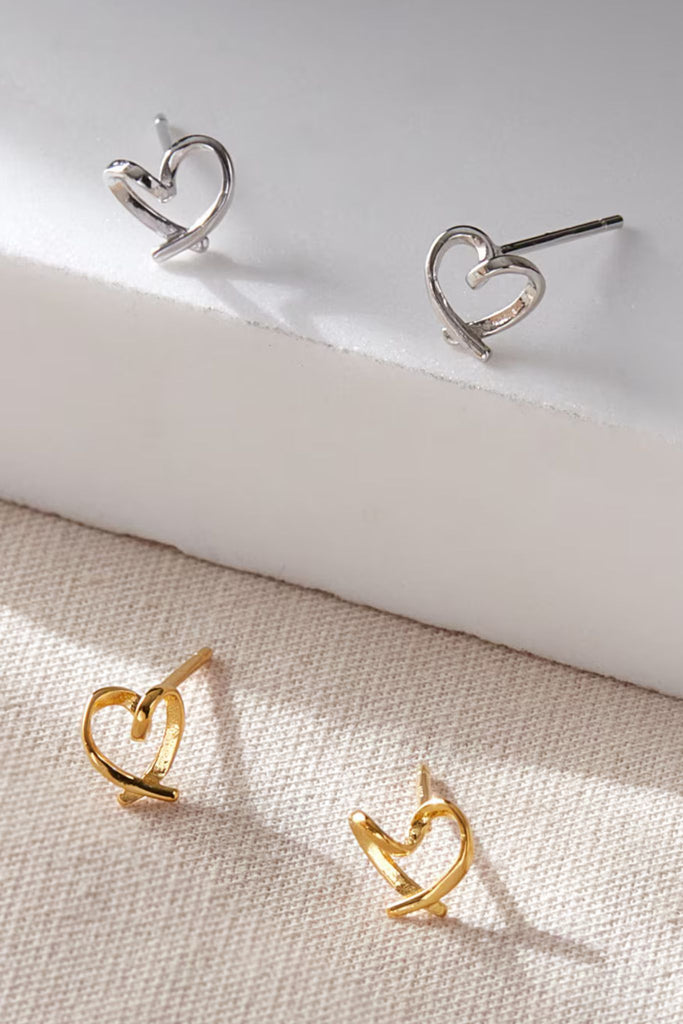 silver and gold love heart shaped stud earrings, the earrings are slightly abstract in shape with a twist in the middle of the love heart