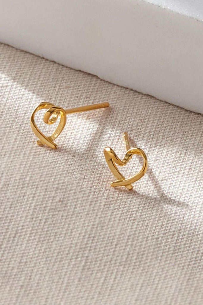 close up of the gold abstract love heart stud earrings, showing closely the swirl twist in the middle of the heart
