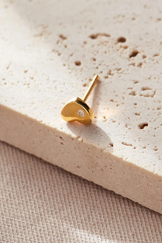 close up of the gold heart stud earring showing the dainty single cz crystal accent