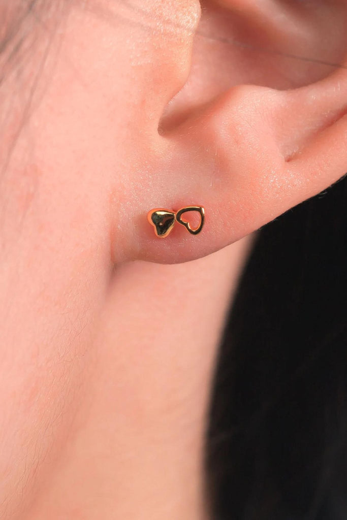 model wearing the gold plated silver double heart stud earring, showing the dainty size of the studs