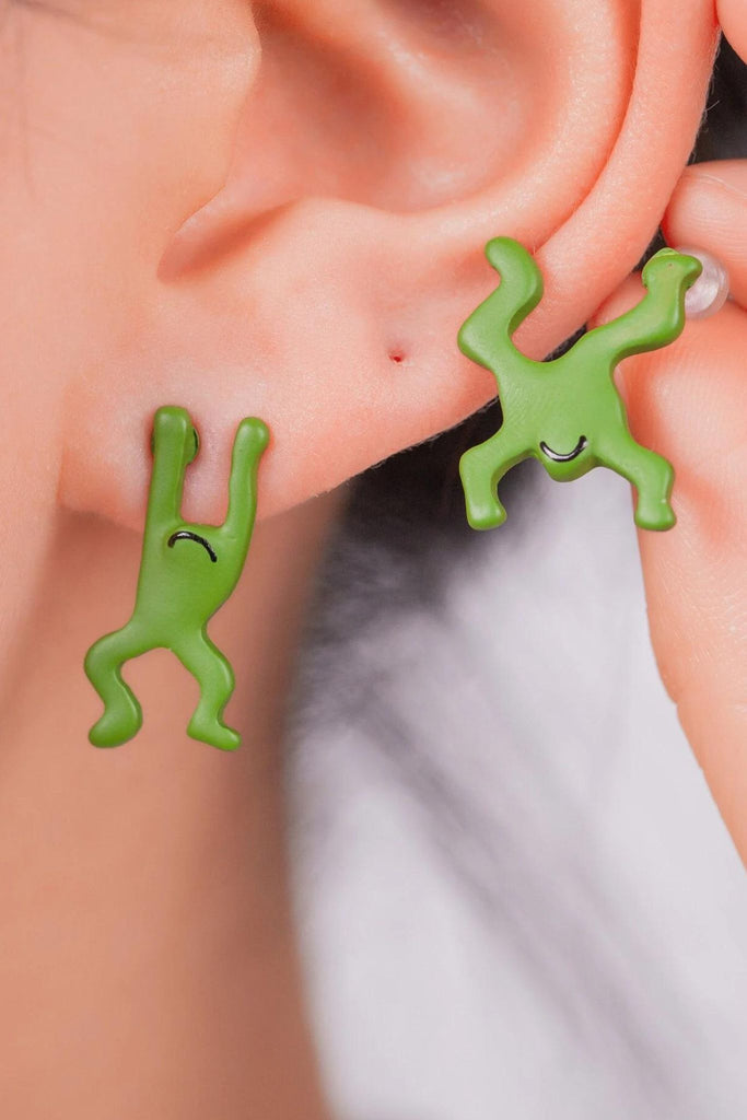 model wearing the green frog earrings, showing the large size of the earrings. they attach like studs but dangle way below the earlobe 