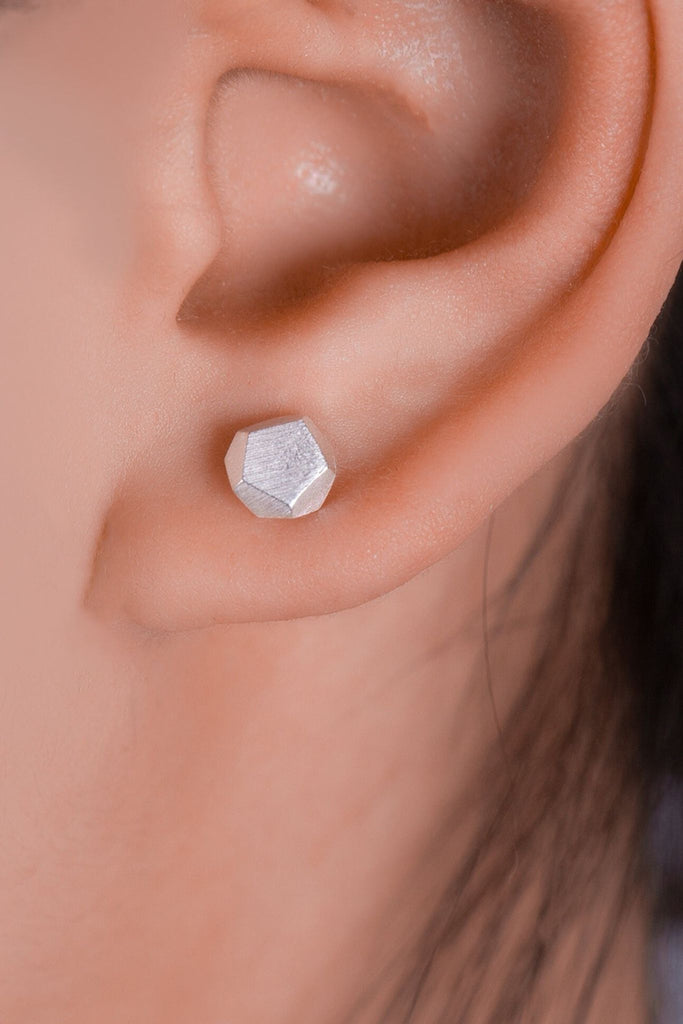 model wearing the silver hammered pentagon stud earring on the earlobe