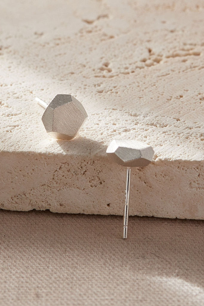 close up of the hammered pentagon stud earrings, showing the three dimensional geometric studs