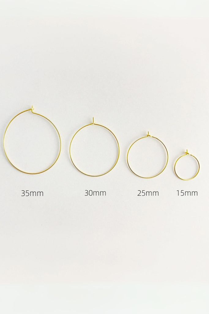 all four sizes of gold hoop earrings laying flat side by side, showing the size difference between them