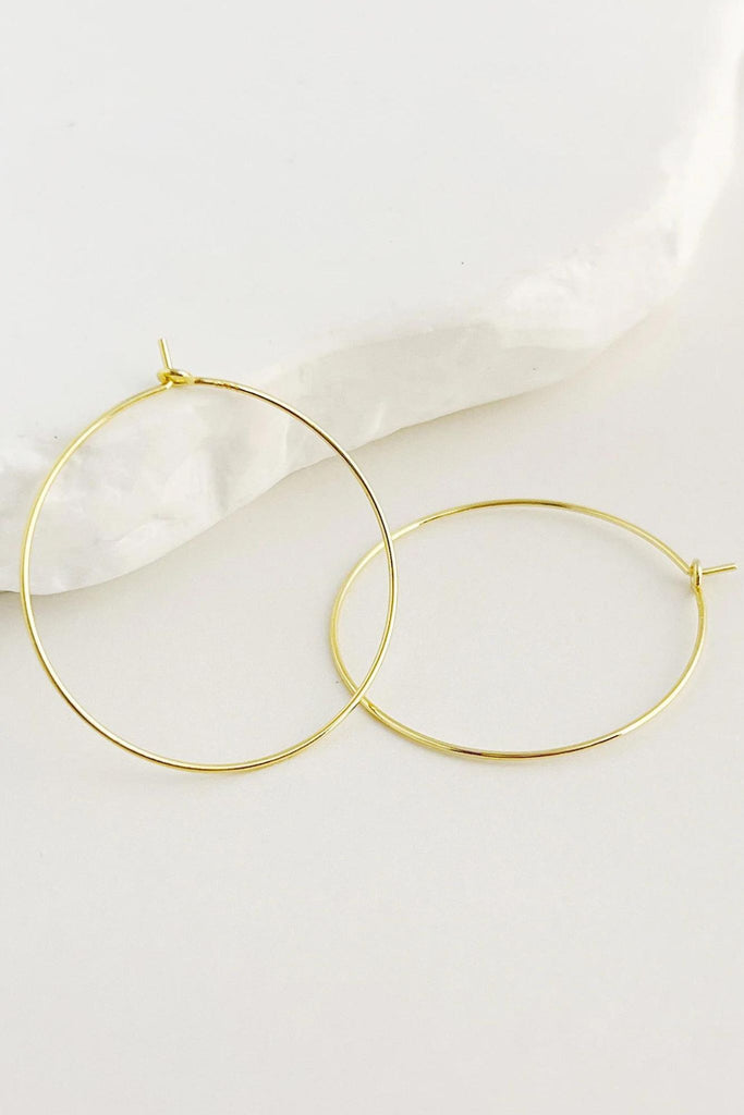 pair of gold coloured thin oversized hoop earrings with latchback closures