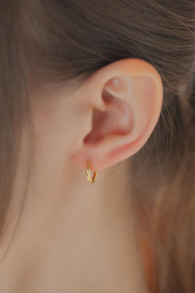 model wearing a plain gold hoop earring in the earlobe