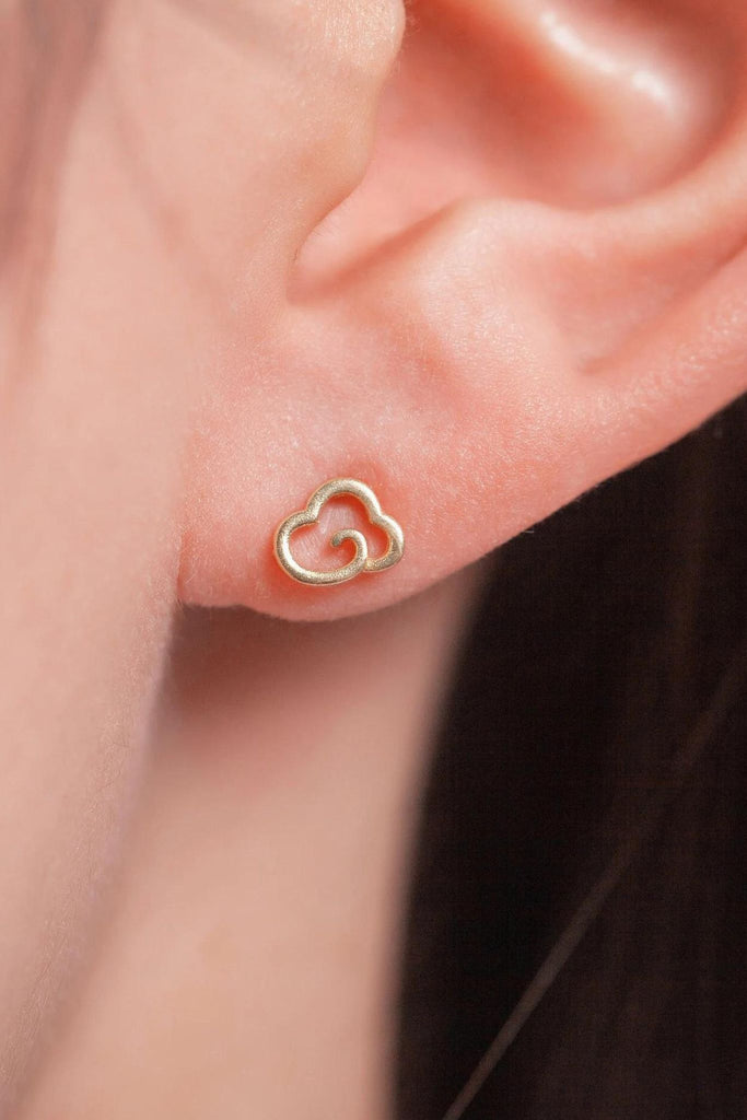 model wearing the gold coloured dainty cloud stud on the earlobe, showing the small size of the earrings