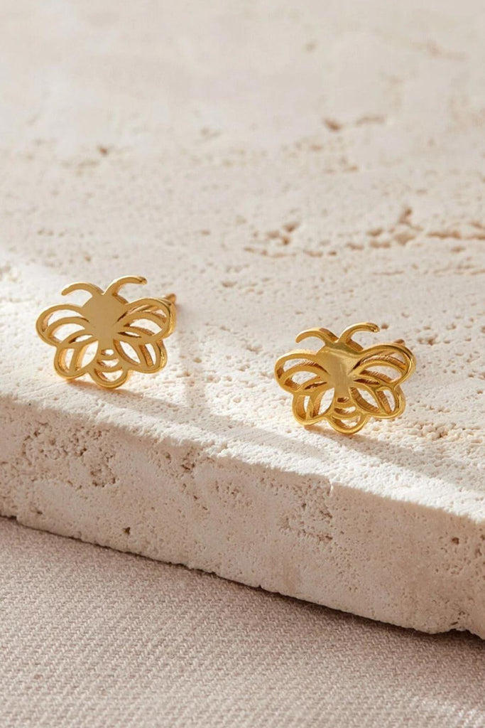 close up of the gold bee stud earrings, showing the open work design of the studs