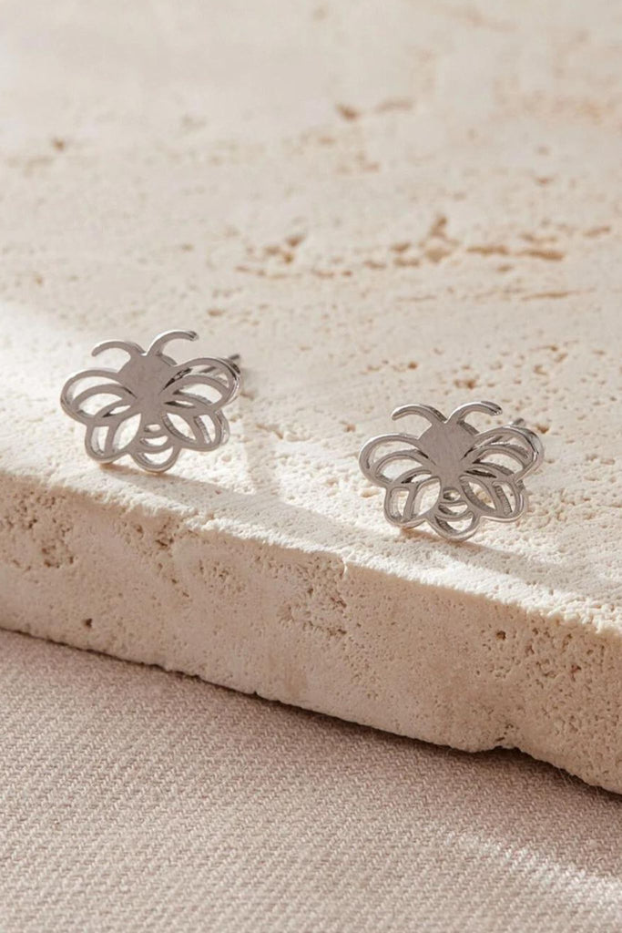 close up of the silver bee stud earrings, showing the open work design of the studs