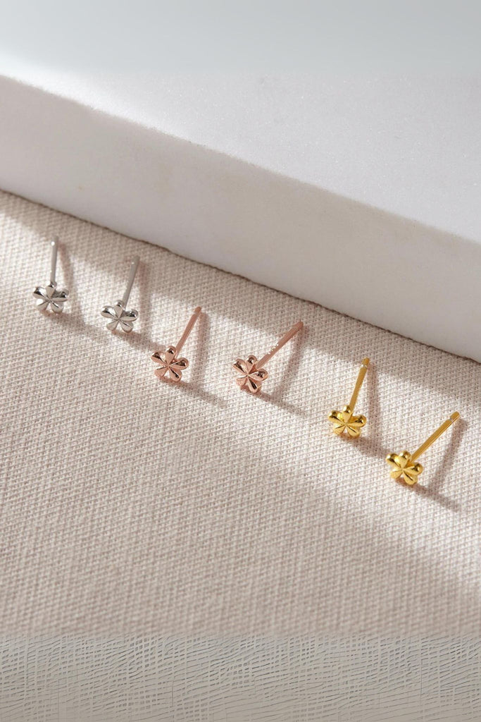 three pairs of dainty five petal floral stud earrings, one pair silver, one gold and one rose gold