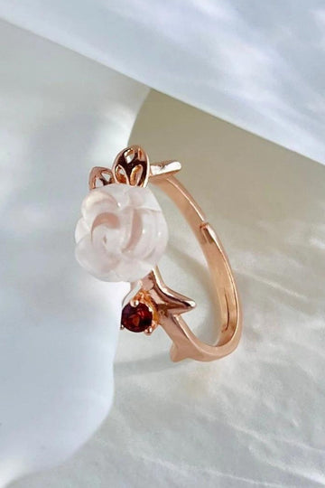 rose gold adjustable ring with a quartz rose flower centred in the middle, with a natural red garnet gemstone accent