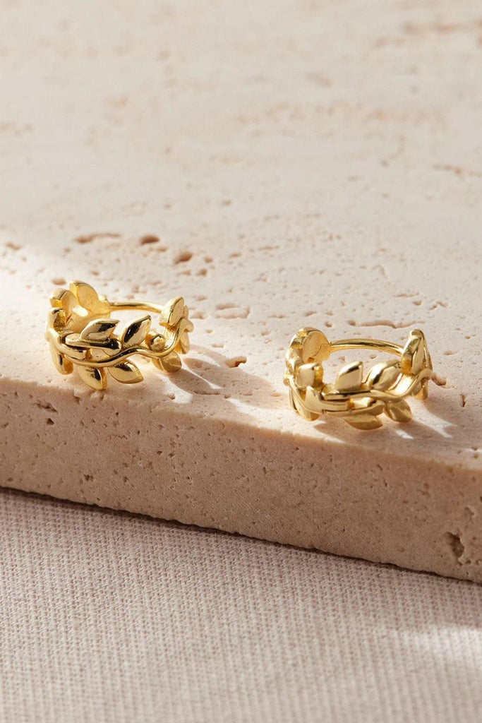 close up of the gold coloured olive leaf huggie hoop earrings