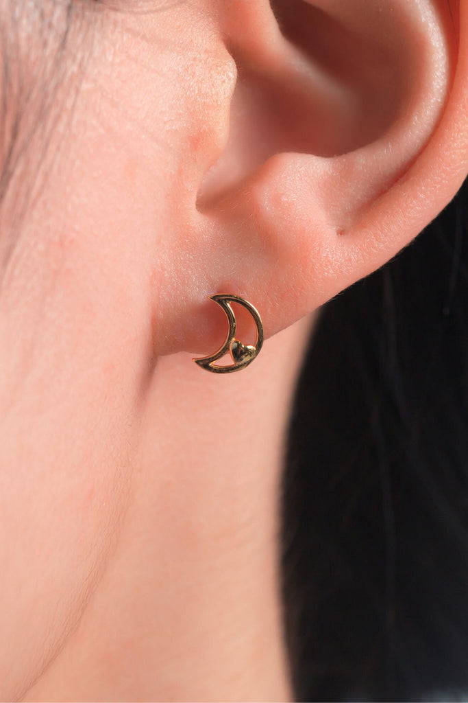 model wearing a gold crescent moon stud earring on the earlobe