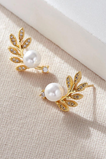 gold coloured leaf stud climber earrings with a large round faux pearl , the earrings are sparkly and adorned with white cz