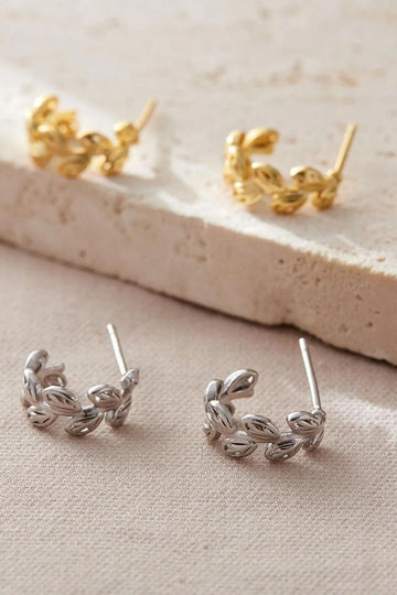 silver and gold half hoop earrings with butterfly backs, the earrings are designed to look like adjoining leaves, the leaves have dainty hollow details giving the jewellery a lattice effect look