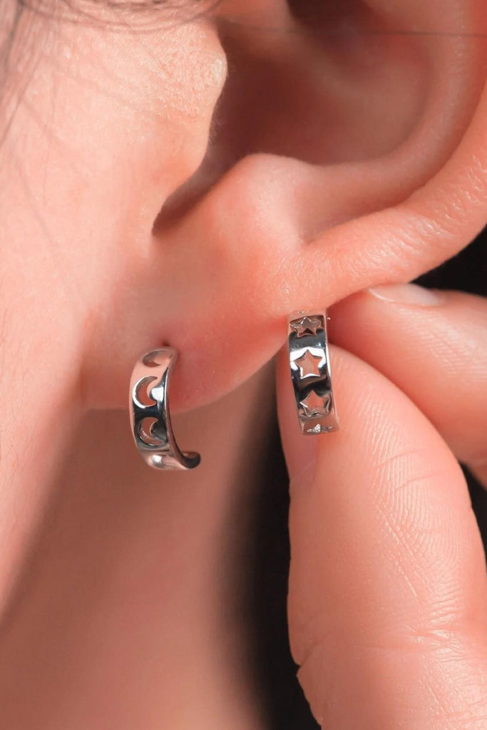 model wearing the silver star and moon mismatched half hoop earrings, showing that each pair has one with stars and one with moons