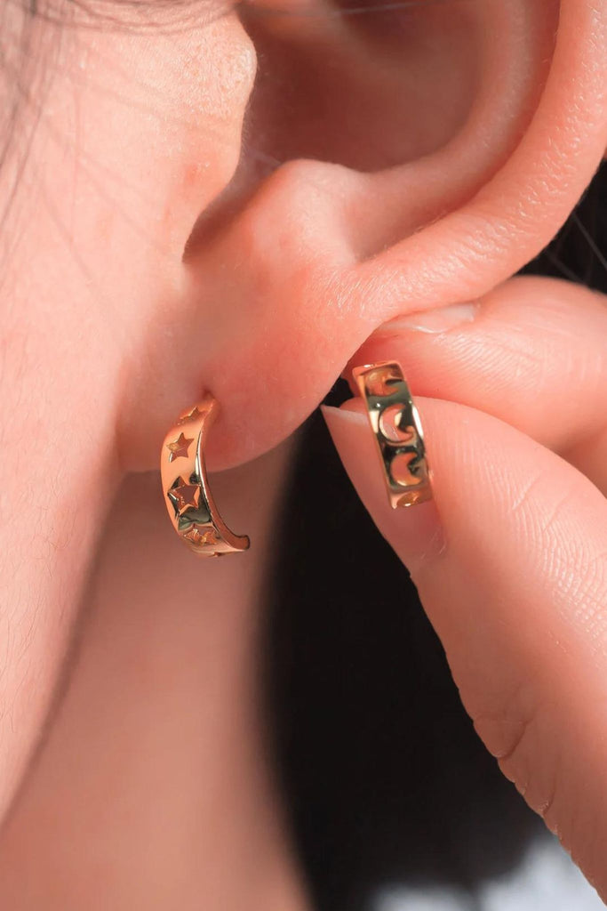 model wearing the gold  star and moon mismatched half hoop earrings, showing that each pair has one with stars and one with moons