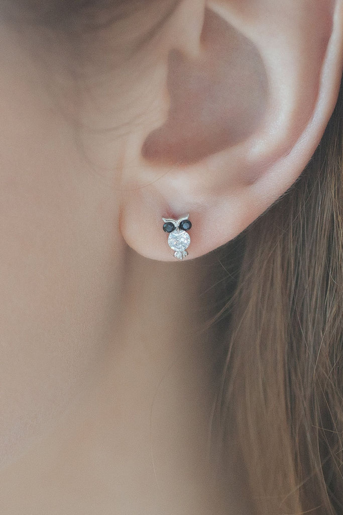 model wearing a silver owl stud on the earlobe showing the dainty size of the jewellery