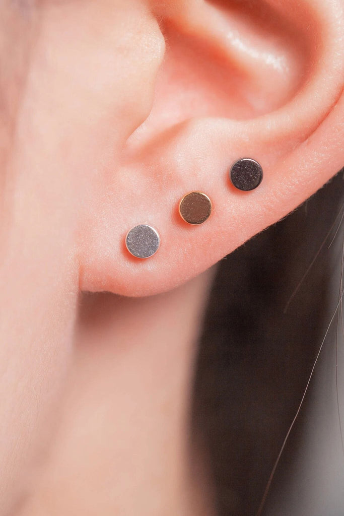 model wearing all three colours of dainty stud, silver, gold and black showing that they can be worn as stacking earrings