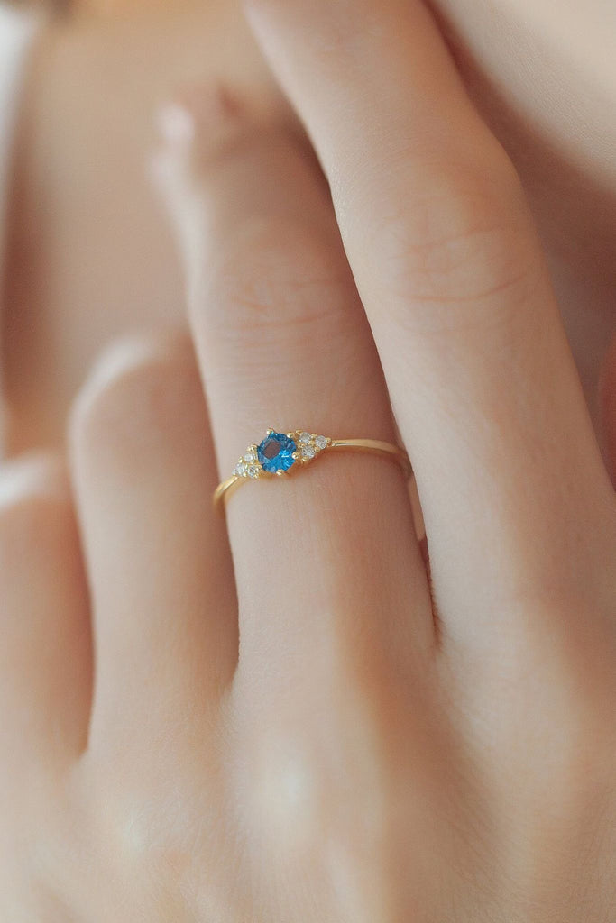 model wearing the blue sparkly gold ring on the middle finger, showing the dainty size of the band