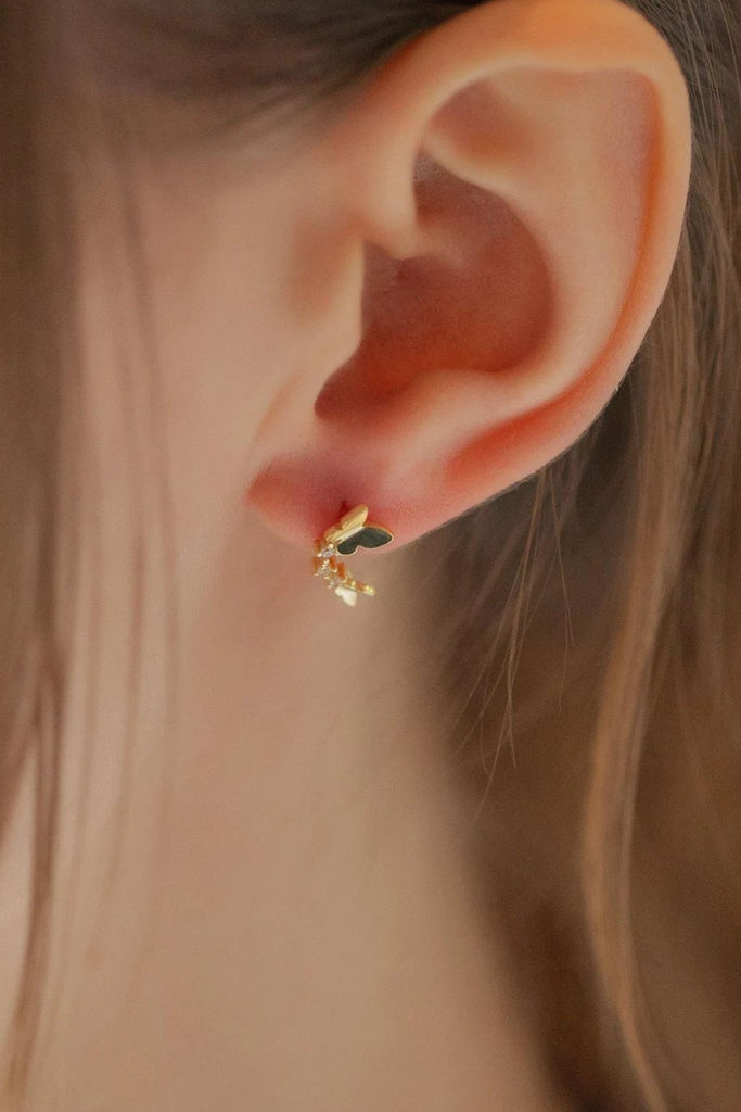 model wearing the gold sparkly dual buttefly stud earring on the earlobe, showing how it looks when worn