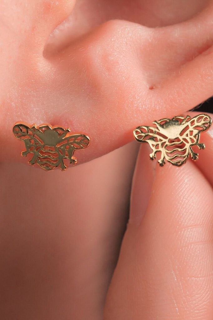 model wearing the gold hollowed out bee stud earrings