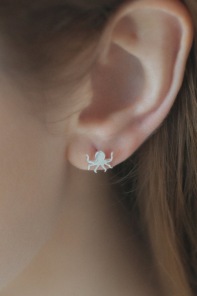 model wearing a silver octopus stud earring on the earlobe showing how they look when worn