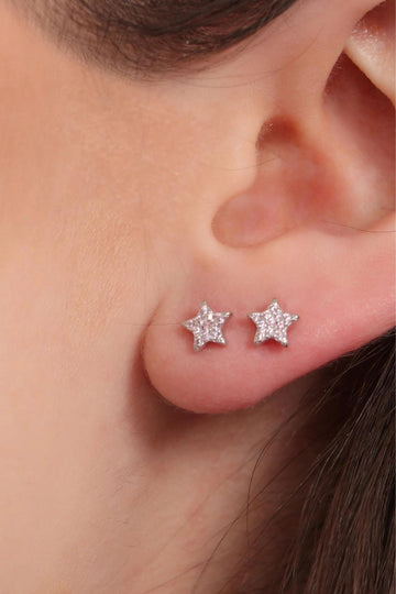 model wearing two sparkly star stud earring on the earlobe, showing the size of the earrings and that they can be worn stacked