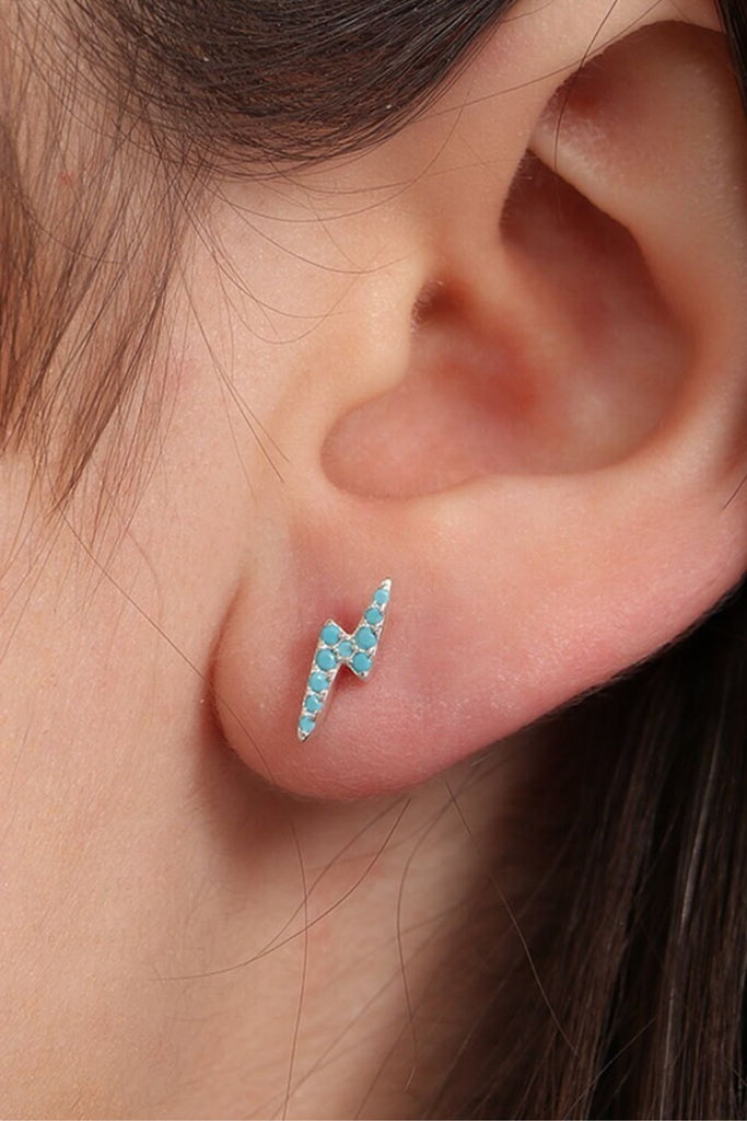 model wearing a turquoise coloured sparkly lighting bolt stud earring on the earlobe