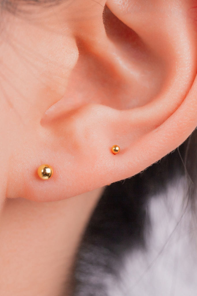 model wearing two of the smallest sizes of gold stud earrings, showing that they can be worn as stacking studs