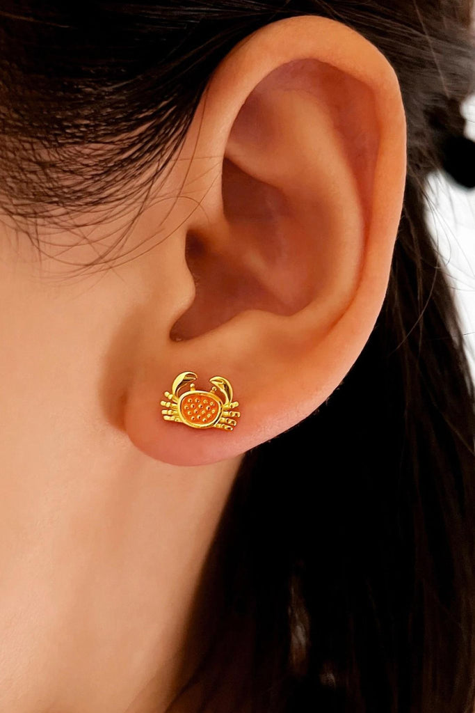 model wearing the gold coloured crab stud earring on the earlobe showing how it looks when worn