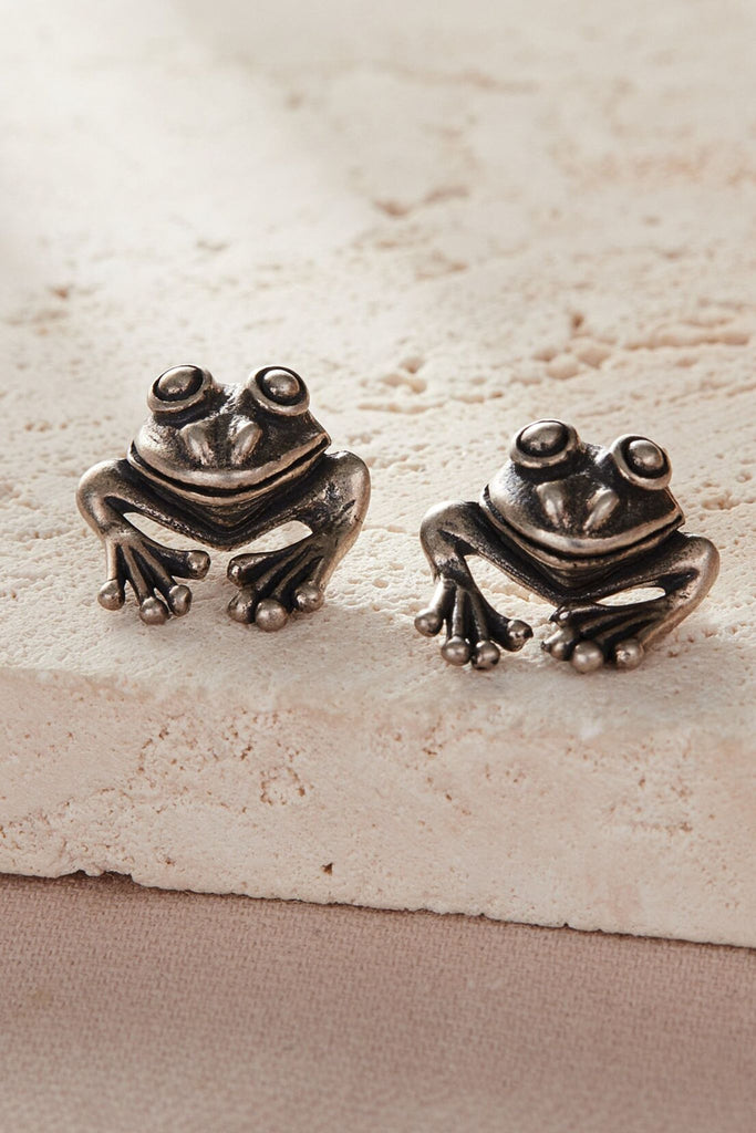 a pair of sterling silver frog earrings, the earrings show the frogs head and front legs