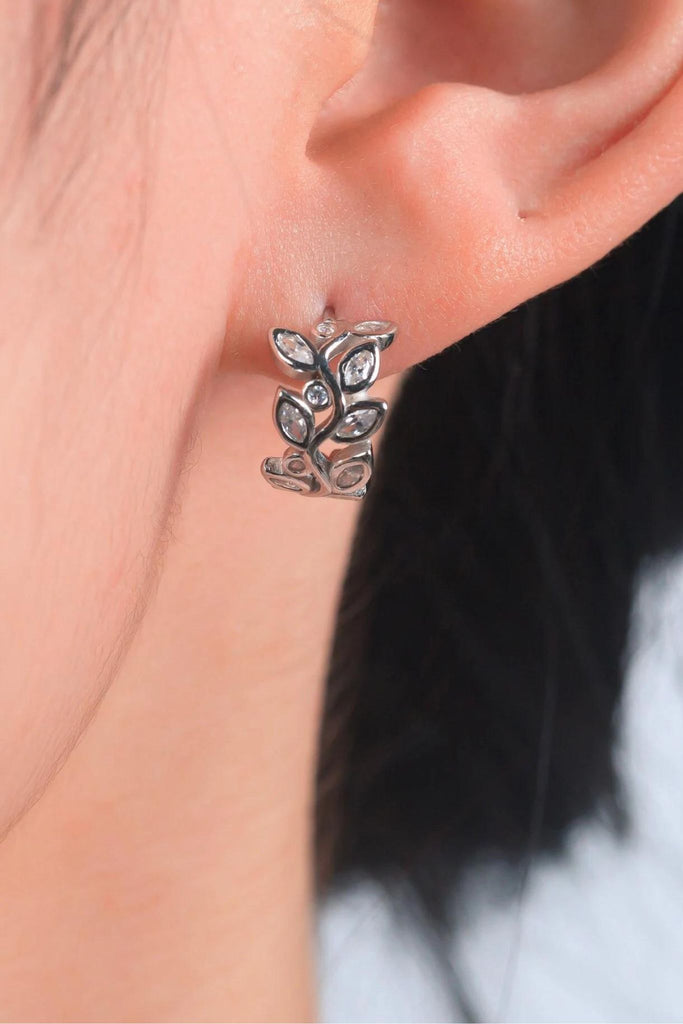 model wearing the silver olive leaf hoop in the earlobe showing a close up of the cz details and showing the size of the earrings