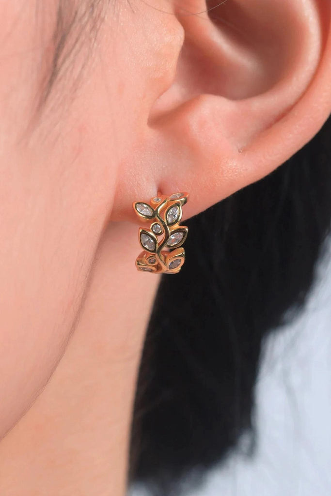 model wearing the gold plated silver olive leaf hoop in the earlobe showing a close up of the cz details and showing the size of the earrings