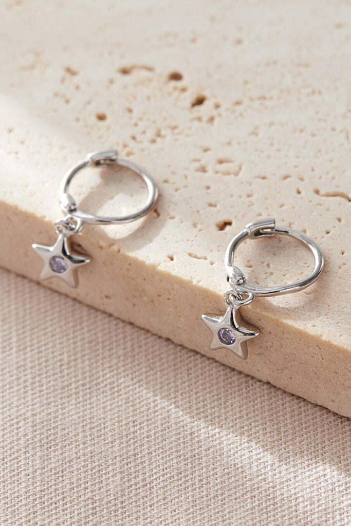 close up of the star charm hoop earrings, showing clearly colourful cz centres, these have white stones in the middle and represent the month of april