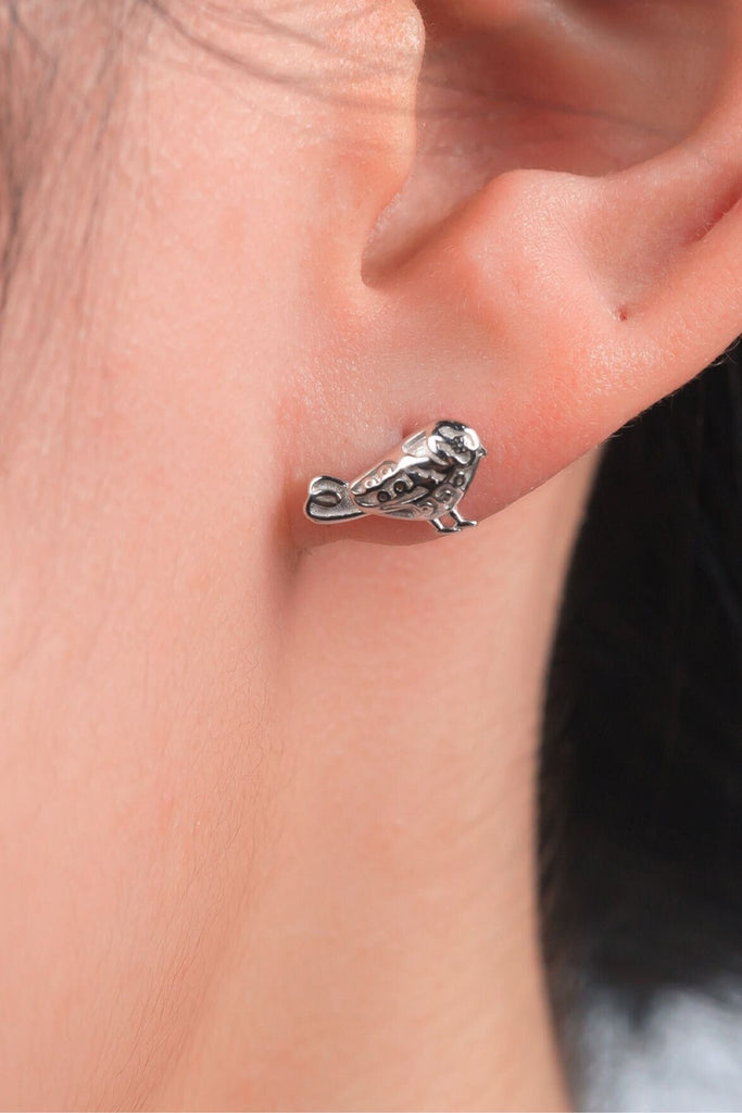 model wearing a silver bird stud earring on the earlobe, showing the dainty size of the earrings