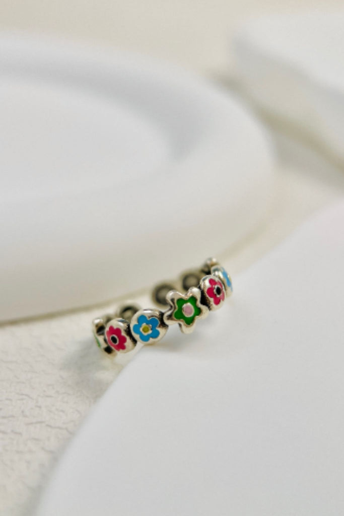 silver ring designed to look like a wreath of reen, pink and blue enamel flowers