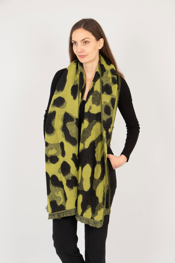 model wearing a lime leopard print scarf draped around the neck, showing that the animal print pattern covers the whole of the scarf