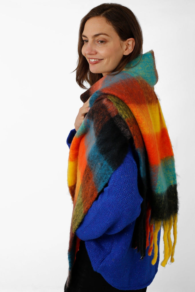 model wearing a multicoloured orange, yellow, winter scarf with tassles