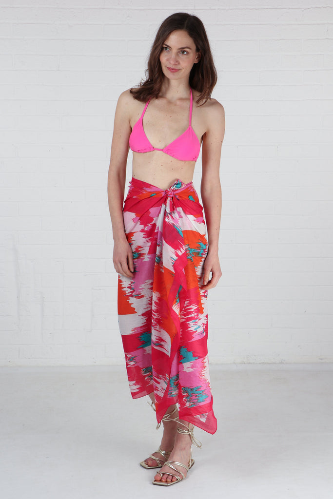 model wearing a pink abstract pattern cotton scarf as a beach sarong