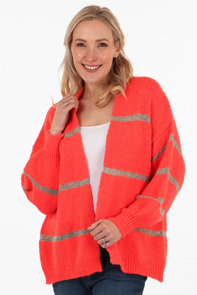 model wearing an open front coral cardigan with a thin gold  knitted glitter stripe throughout