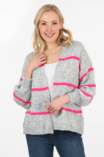 model wearing a grey open front short cardigan with fuchsia pink horizontal stripes